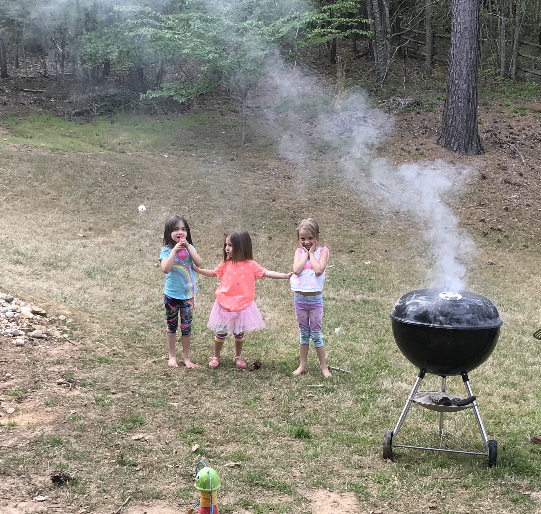 Children playing in backyard while grilling